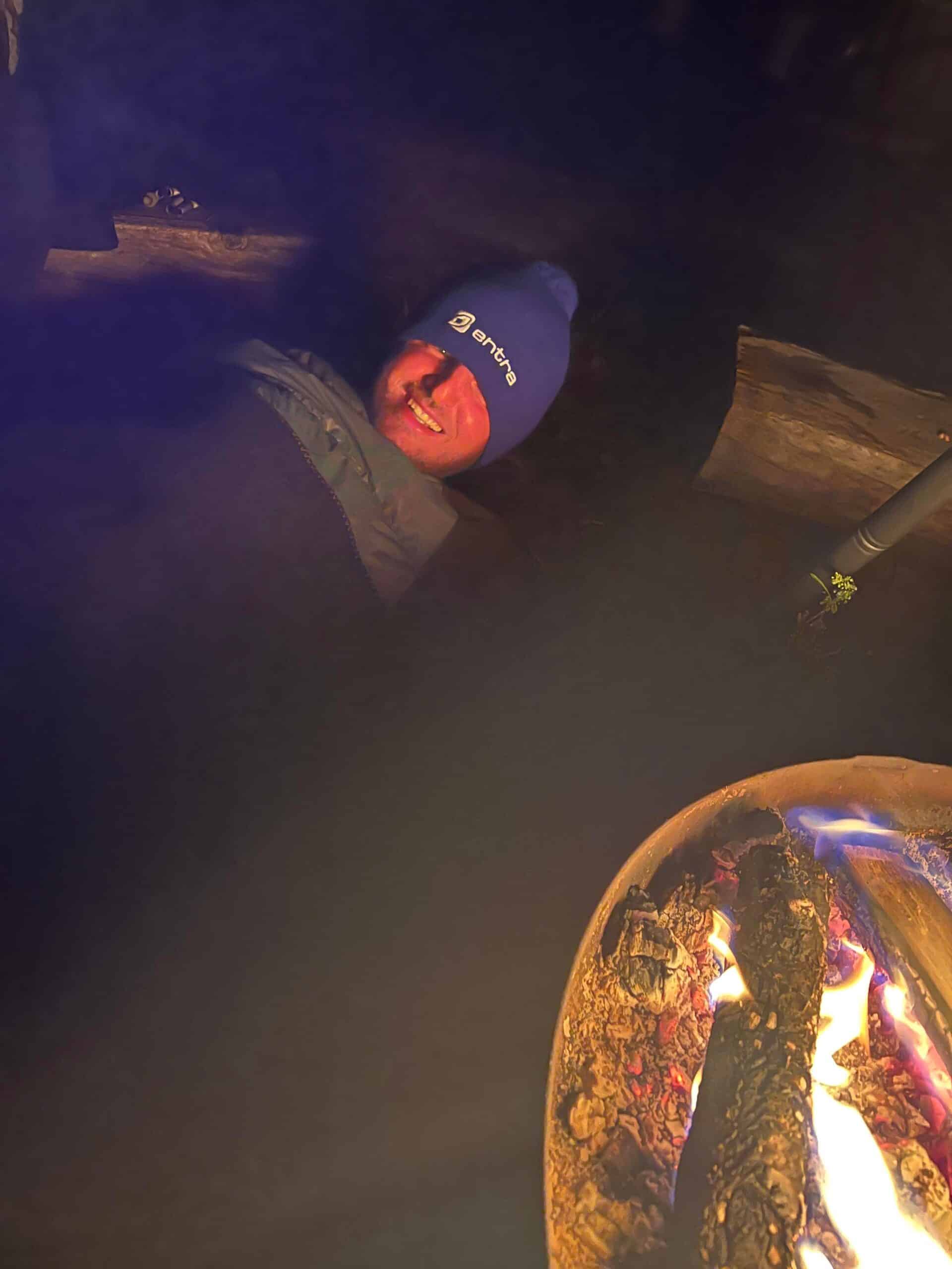 Edis ligger i en sovepose ved et bål